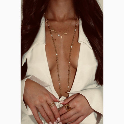 Close-up of a person wearing a white outfit with gold jewelry and rings.