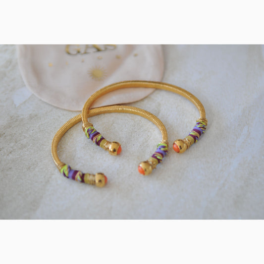 Gold bangles with colorful beads on a light background