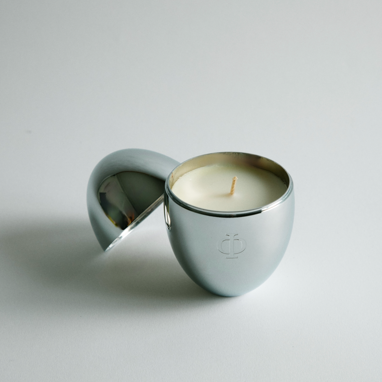 Silver candle holder with a lit candle on a gray background