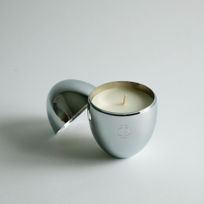 Silver candle holder with a lit candle on a gray background