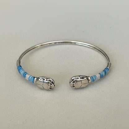 Silver bracelet with blue accents on a light gray background