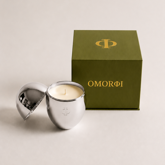 Silver egg shaped metallic candle with luxury green gift box beside it