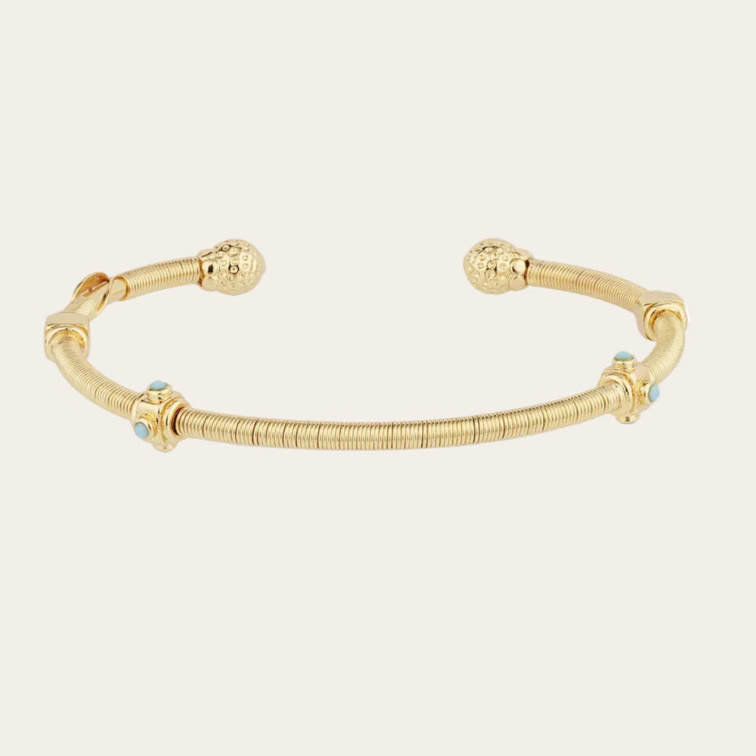 gold bangle with turquoise stones on neutral background