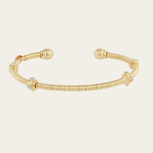 gold bangle with turquoise stones on neutral background