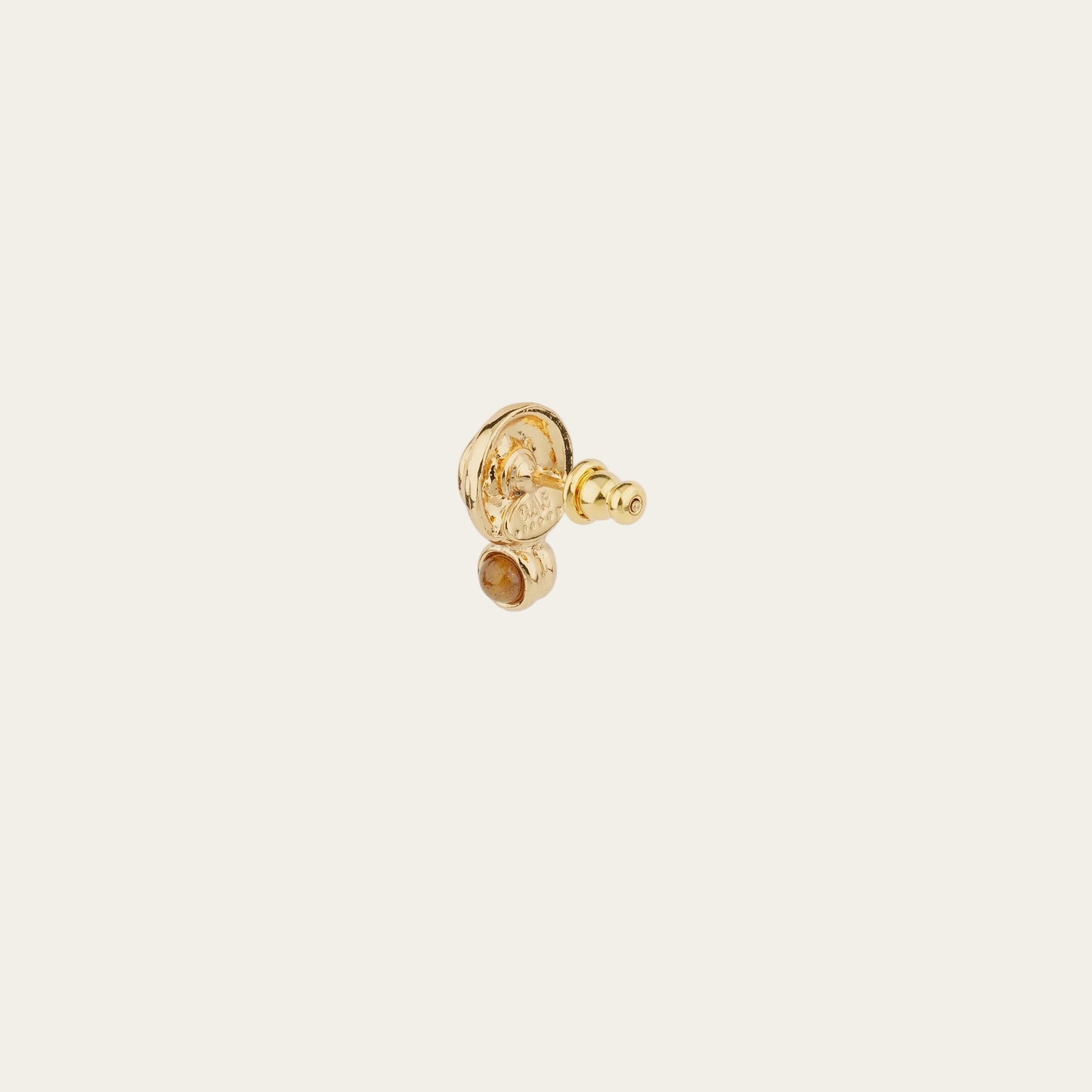 Gold earring on a light beige background