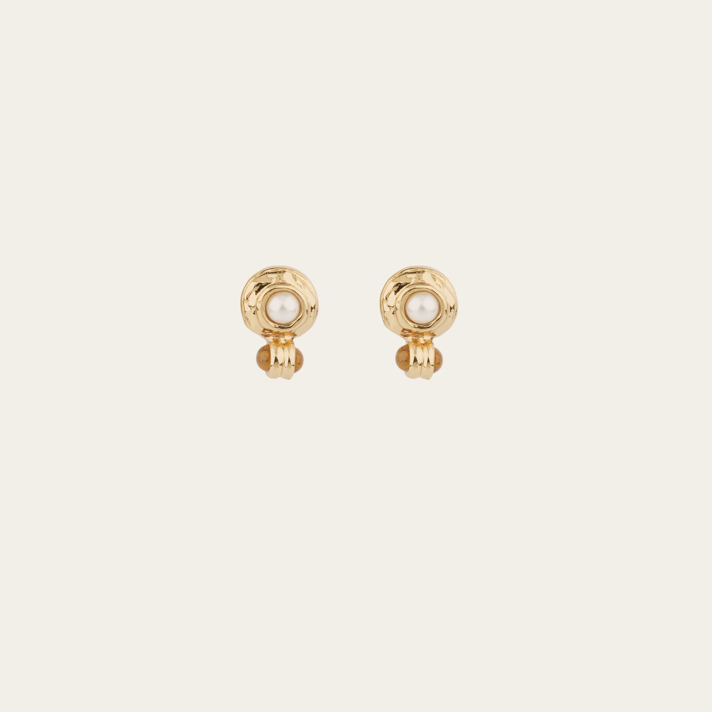 Gold earrings with pearl centers on a light beige background
