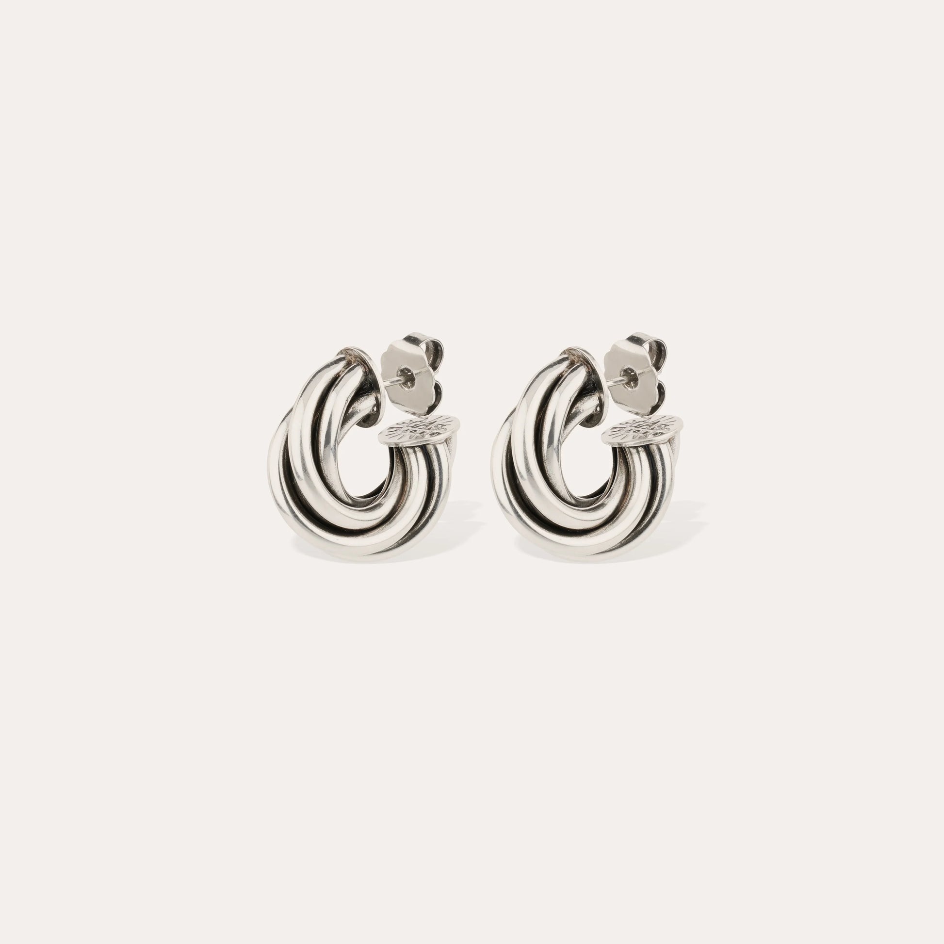 Pair of silver hoop earrings on a light beige background