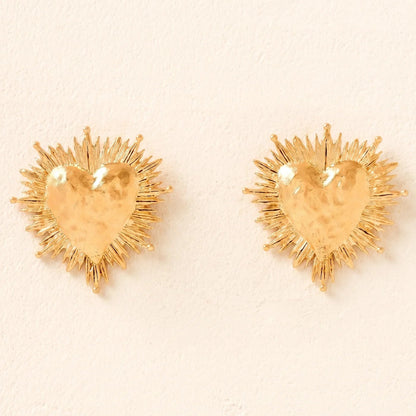 Pair of gold heart-shaped earrings on a beige background