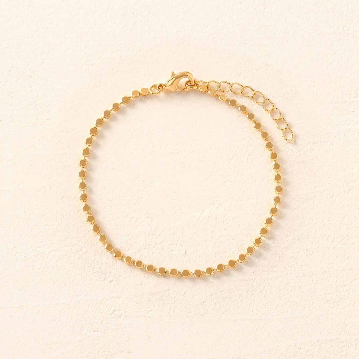 Gold bracelet on a beige background