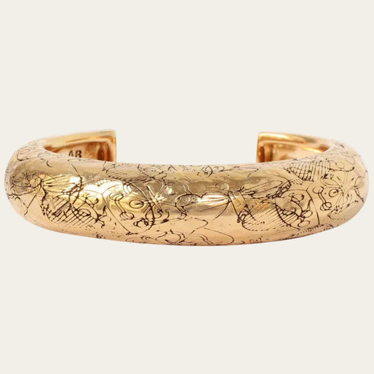 Gold bracelet with engraved design on a white background