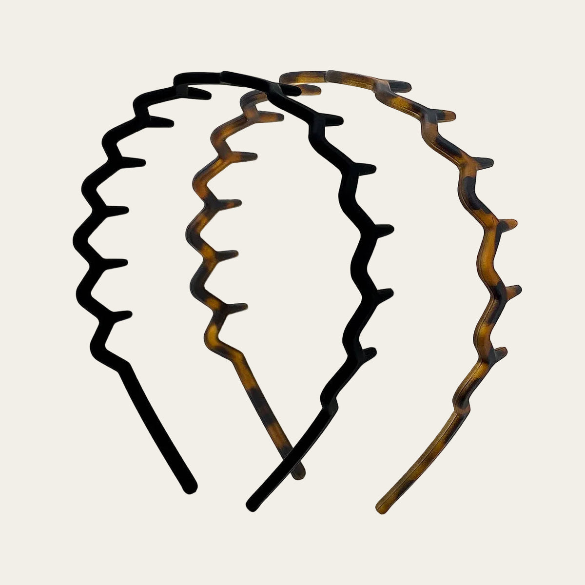 Two wavy headbands in black  and tortoiseshell patterns, arranged on a light gray background.