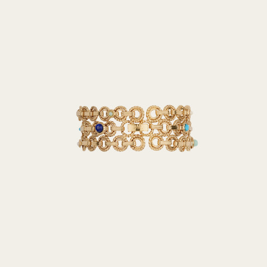 Gold chain bracelet with blue and turquoise stones on a beige background