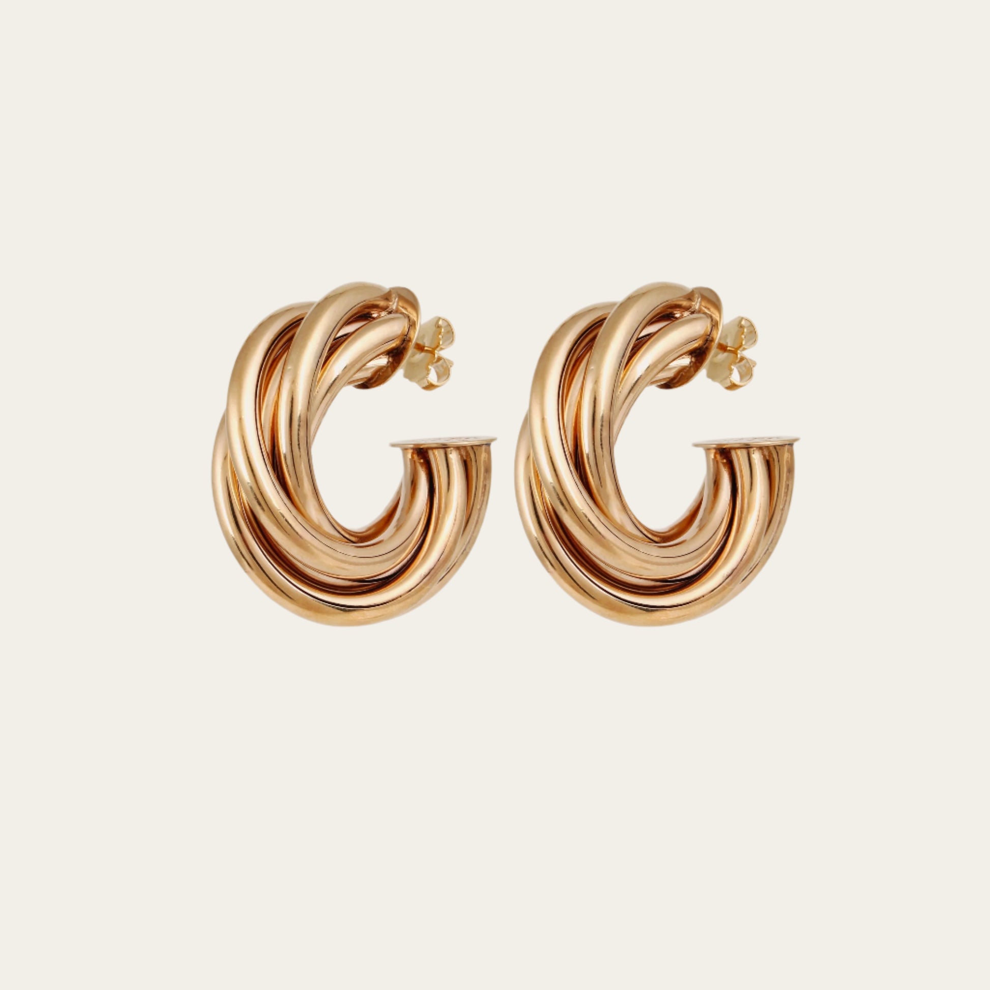 Gold hoop earrings on a light beige background