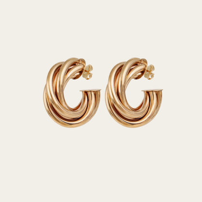 Gold hoop earrings on a light beige background