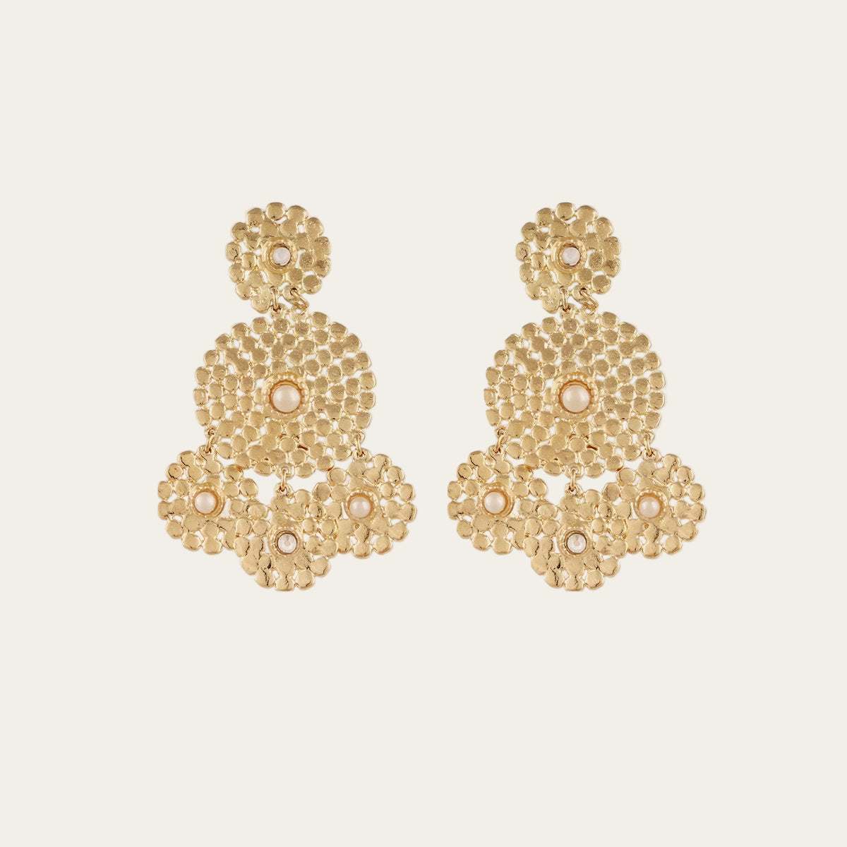 Gold earrings with a textured design on a light beige background