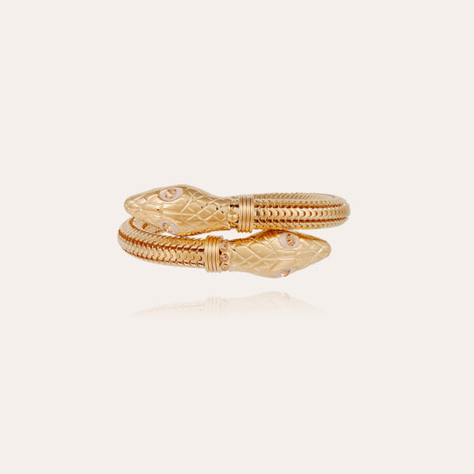 Gold snake-shaped bracelet on a light beige background