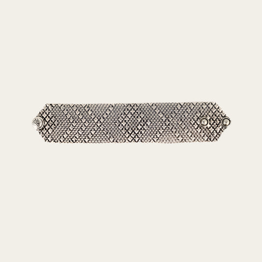 Silver bracelet with a textured pattern on a light gray background