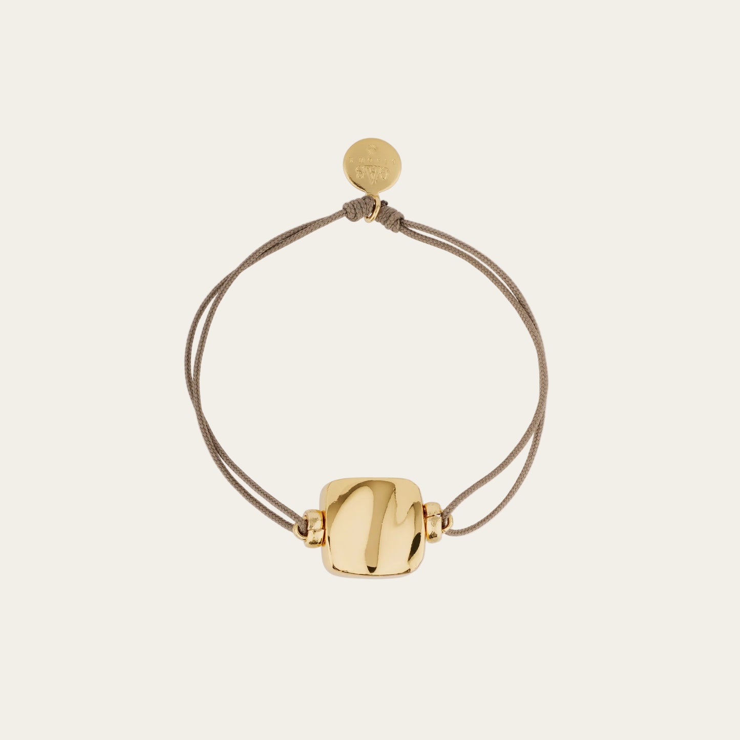 Gold bracelet with a round clasp on a beige background