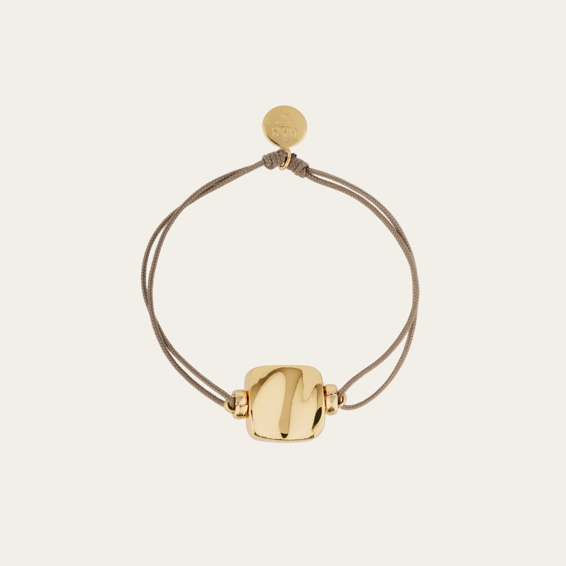 Gold bracelet with a round clasp on a beige background
