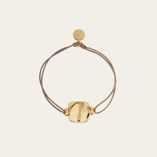 Gold bracelet with a round clasp on a beige background