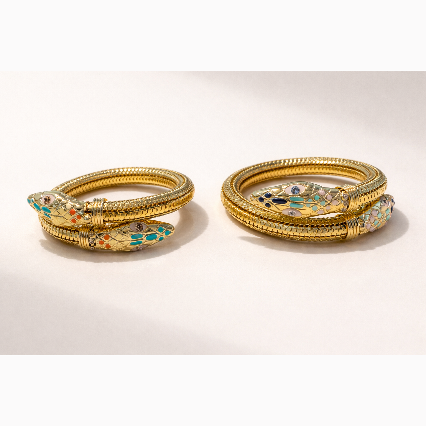 Two gold bangles with decorative elements on a white background
