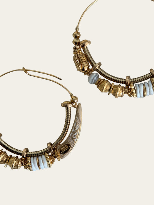 Gold hoop earrings with decorative elements on a gray surface