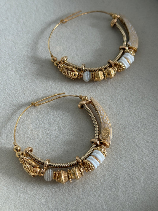 Pair of ornate gold hoop earrings on a gray background