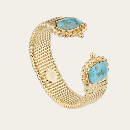 A gold-toned cuff bracelet featuring two oval turquoise stones in ornate settings, displayed on a clean white background.