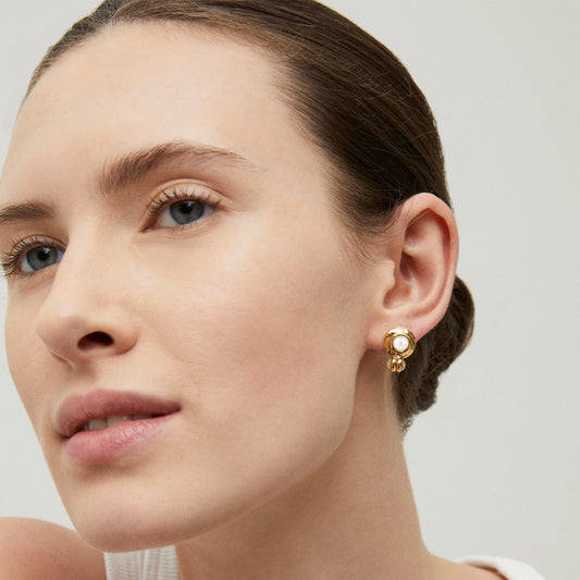 Close-up of a woman wearing gold earrings with a neutral background