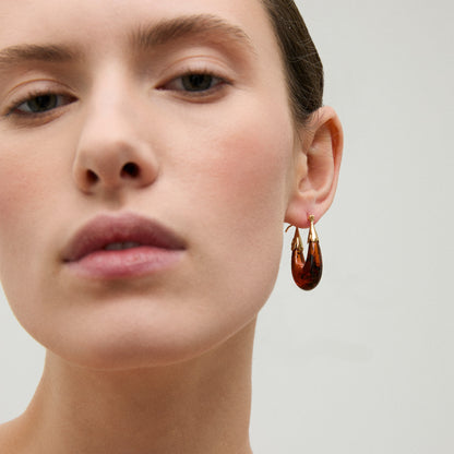 Close-up of a woman wearing a gold earring with a clear background