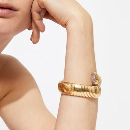 Gold bracelet on a person's wrist with a neutral background