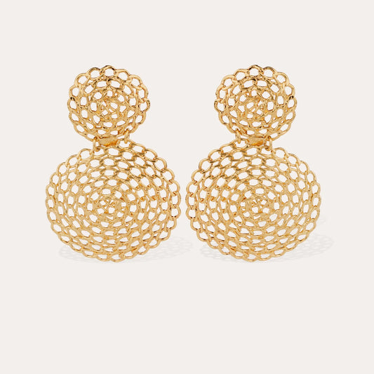 Gold earrings with intricate design on a light beige background
