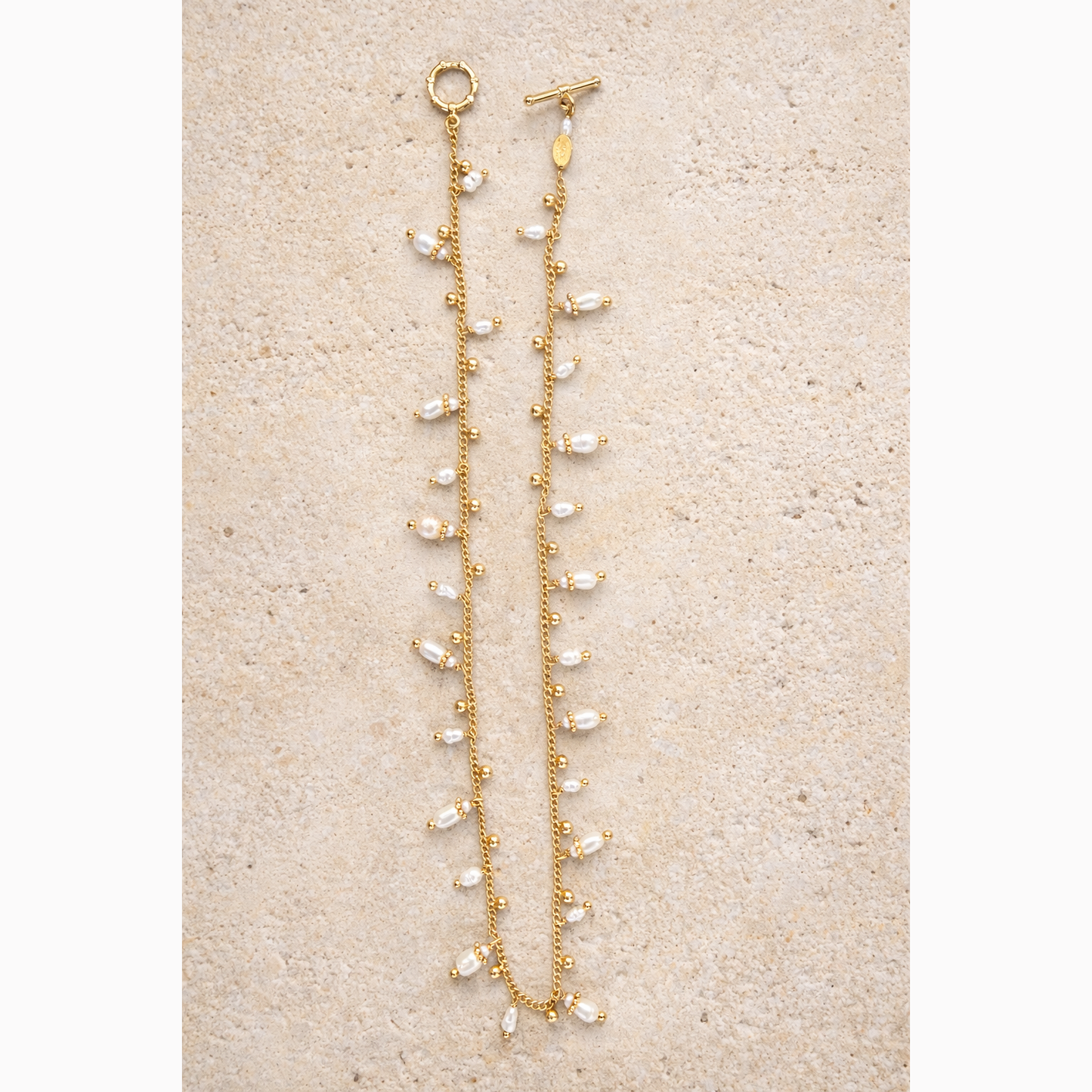 Gold necklacewith pearl-like beads on a beige surface