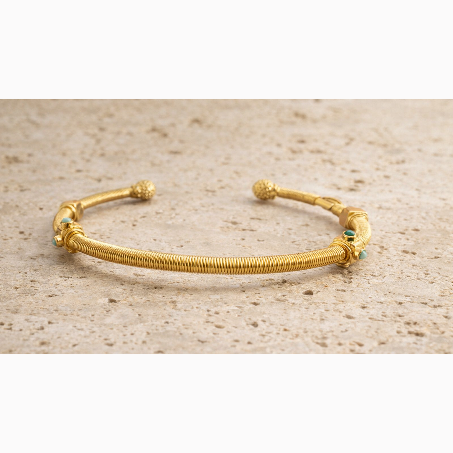 Gold bracelet with small green stones on a beige surface