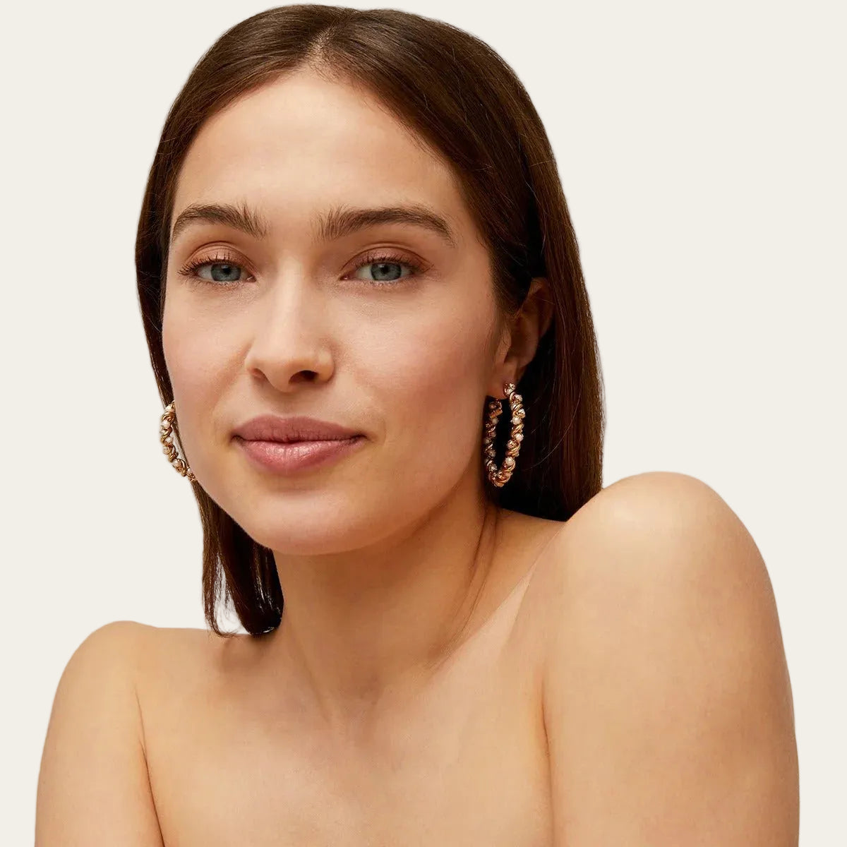 Woman wearing gold hoop earrings against a neutral background