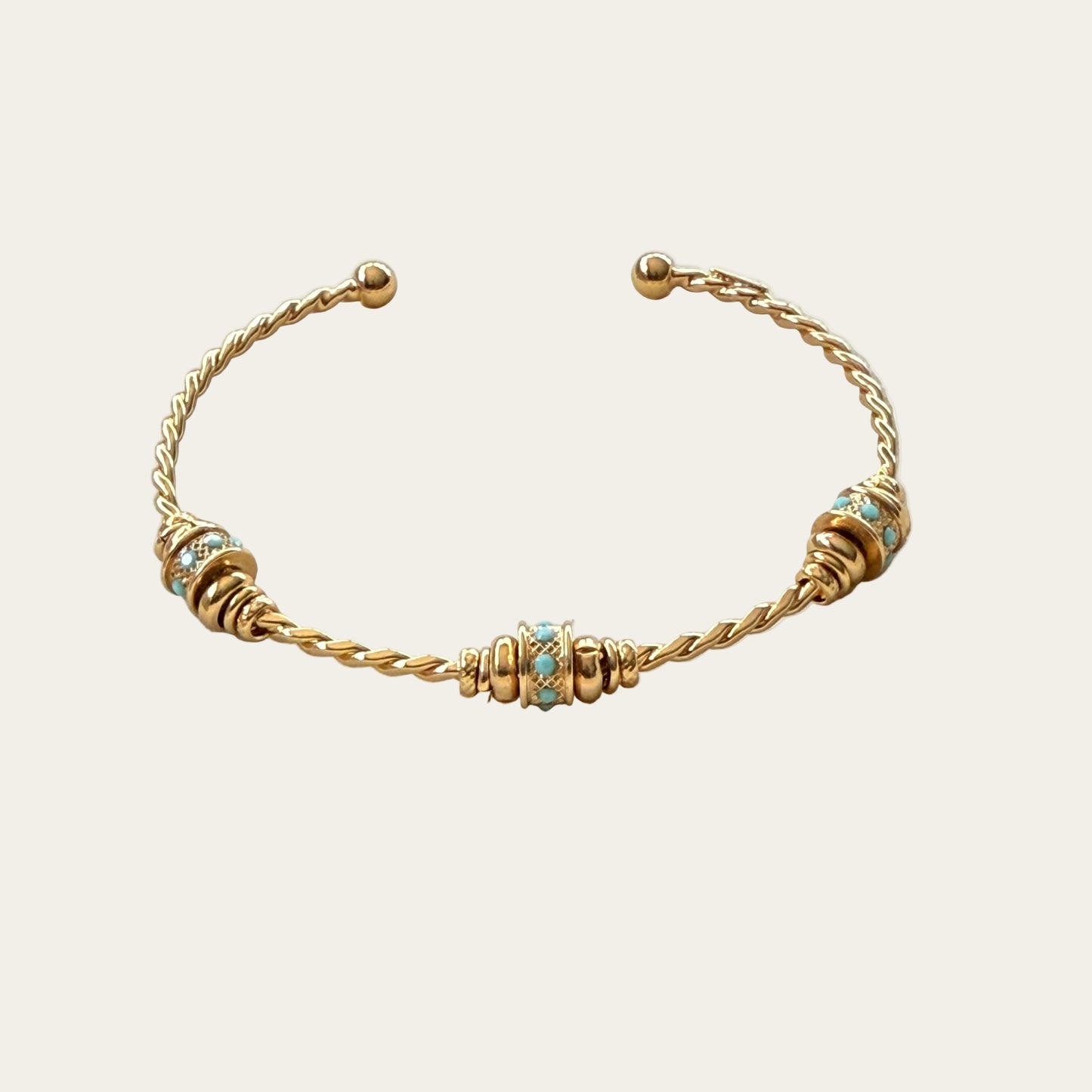 Gold bracelet with turquoise beads on a beige background