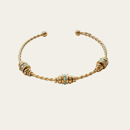 Gold bracelet with turquoise beads on a beige background