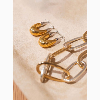Gold and silver hoop earrings on a beige fabric background