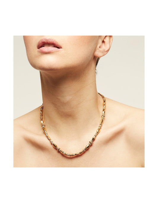 Gold chain necklace worn by a person on a neutral background