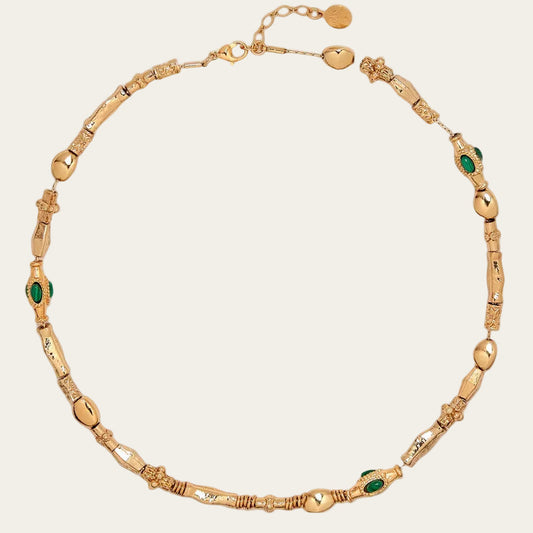 Gold necklace with green gemstones on a white background