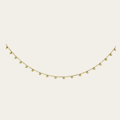 Gold necklace with small beads on a white background
