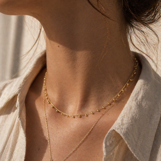 Close-up of a person wearing a delicate gold necklace with a subtle background.
