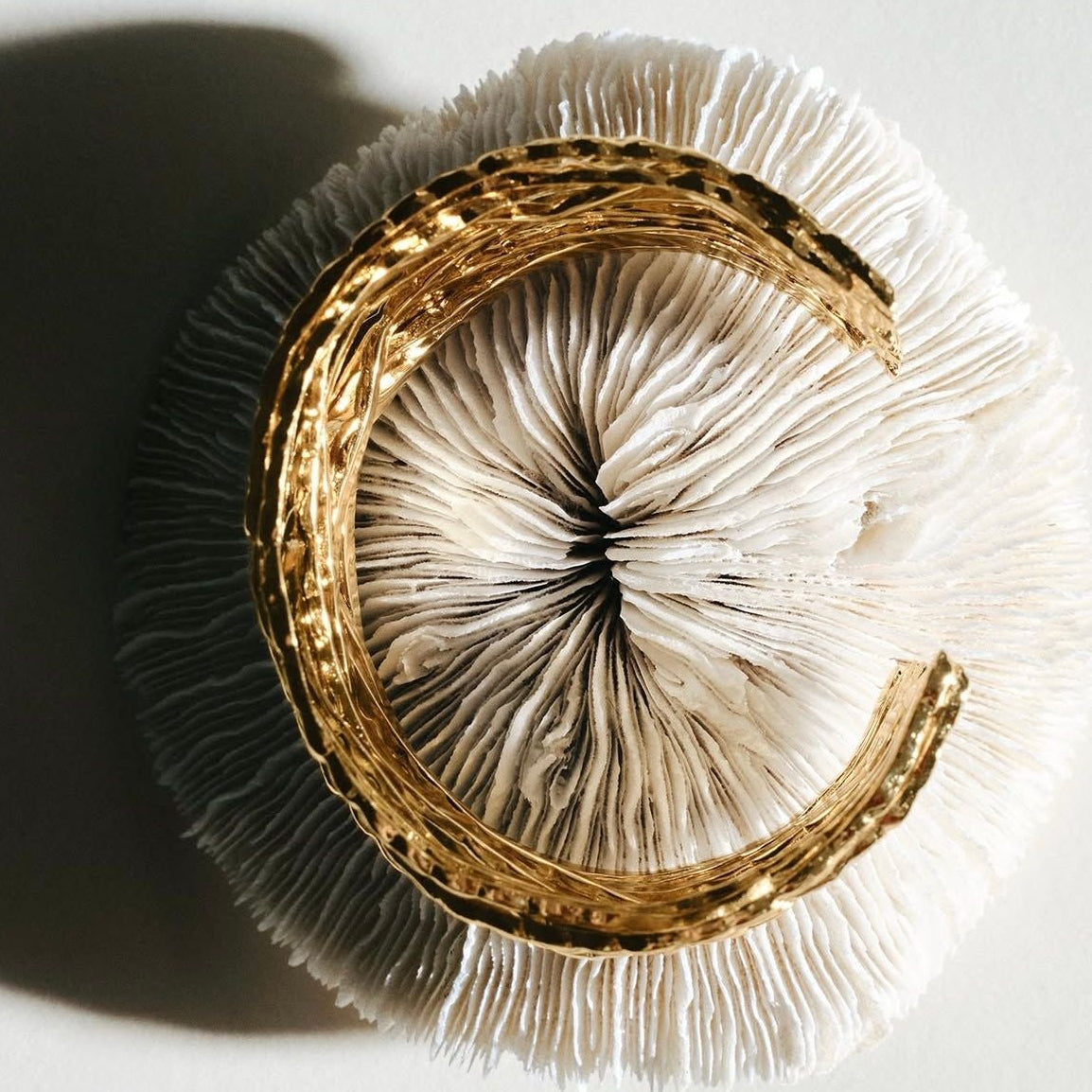 Close-up of a gold rsculptural cuff on a white background