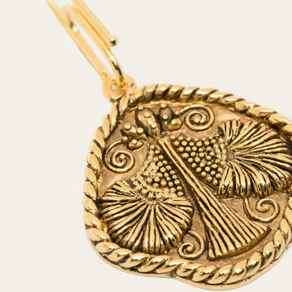 Gold pendant with intricate designs on a white background