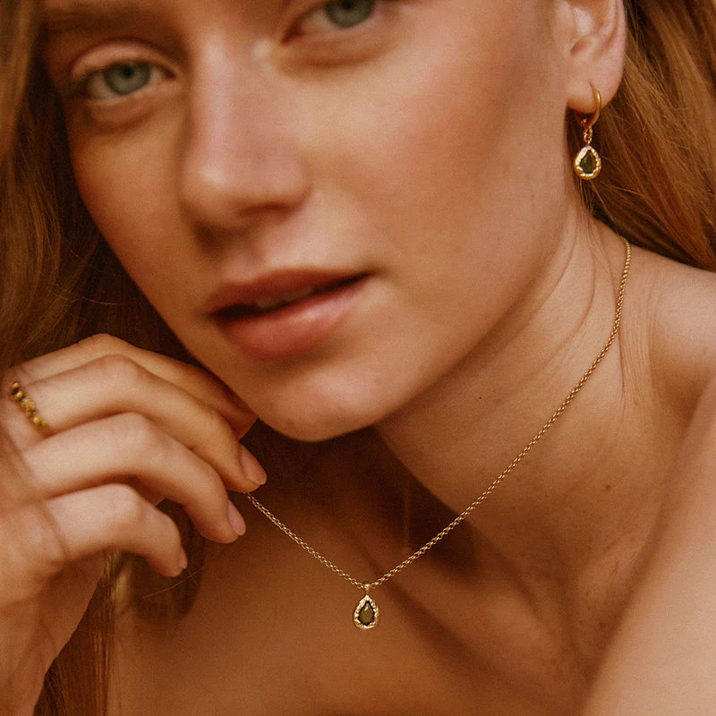 Close-up of a woman wearing gold jewelry including earrings and a necklace.