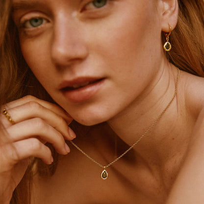 Close-up of a woman wearing gold jewelry including earrings and a necklace.