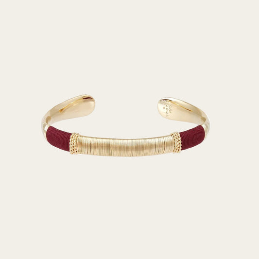 gold bracelet with coloured threads on cream background