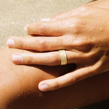 Hand with a gold ring on a sunlit surface