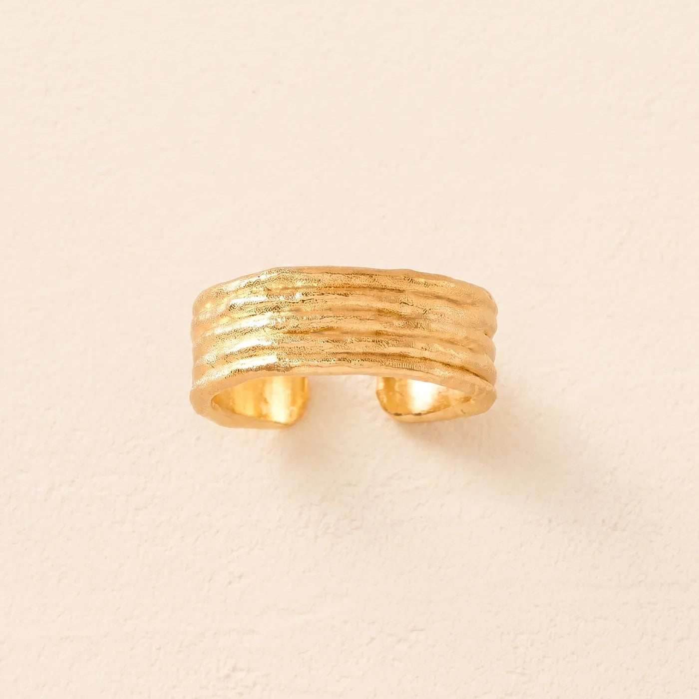 Gold textured ring on a beige background