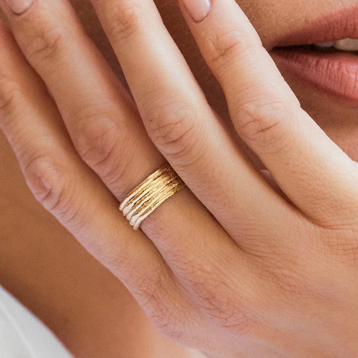Close-up of a hand wearing a gold ring with a blurred background
